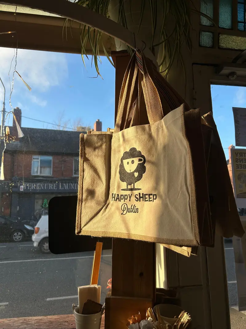 Happy Sheep Dublin tote bags hanging in the café window, with the street outside